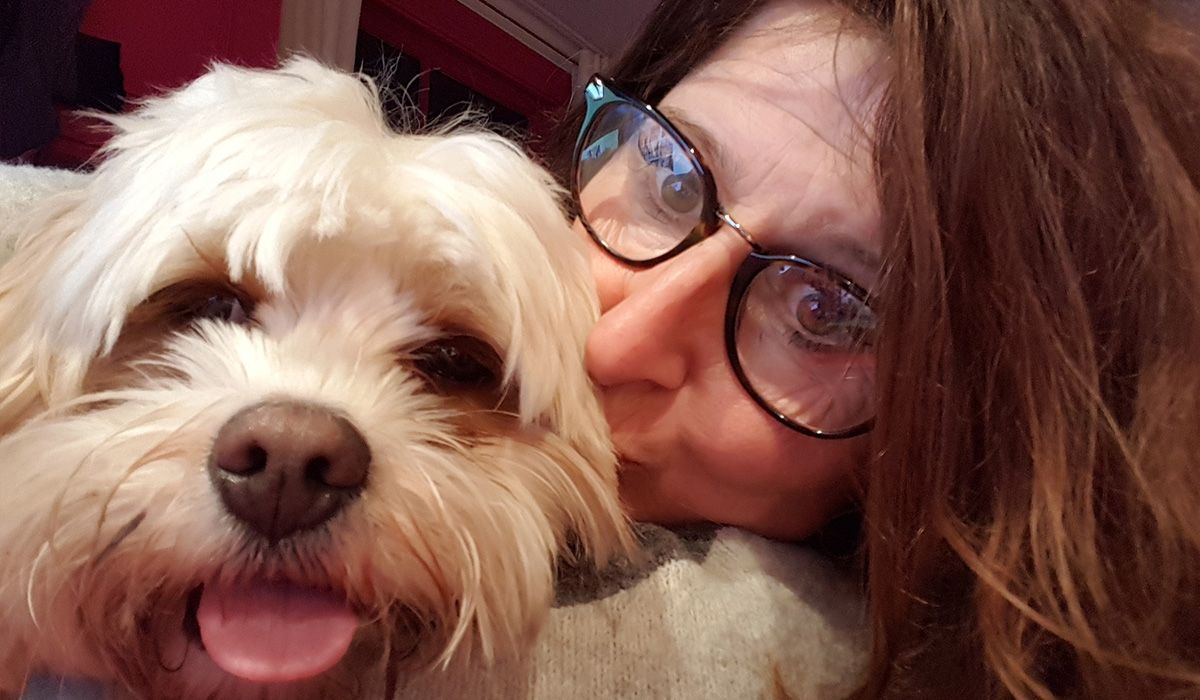 Melanie kisses Pepper on the head while they cuddle and both look at the camera