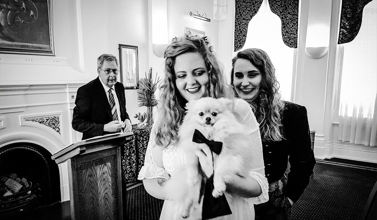 Rupert, wearing a black bow tie, is carried by Katie at the civil ceremony