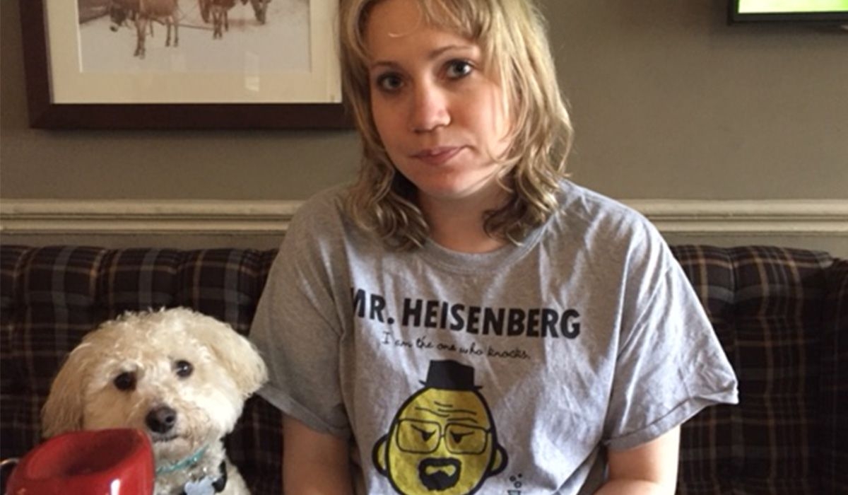 A white fluffy dog and a person sit on a sofa