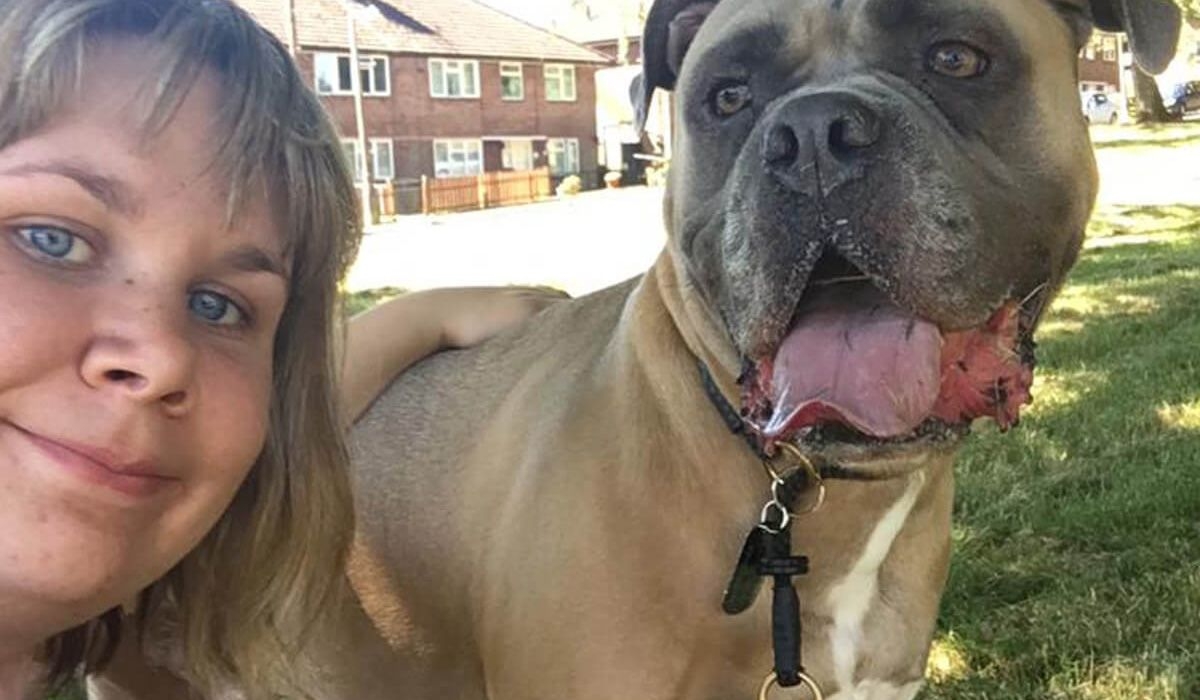 A woman and a dog pose for the camera in a park