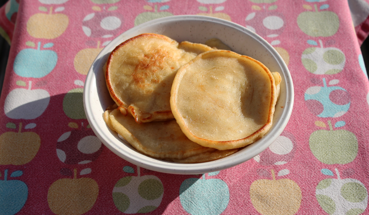 A bowl of fluffy pancakes sitting on the table outside.