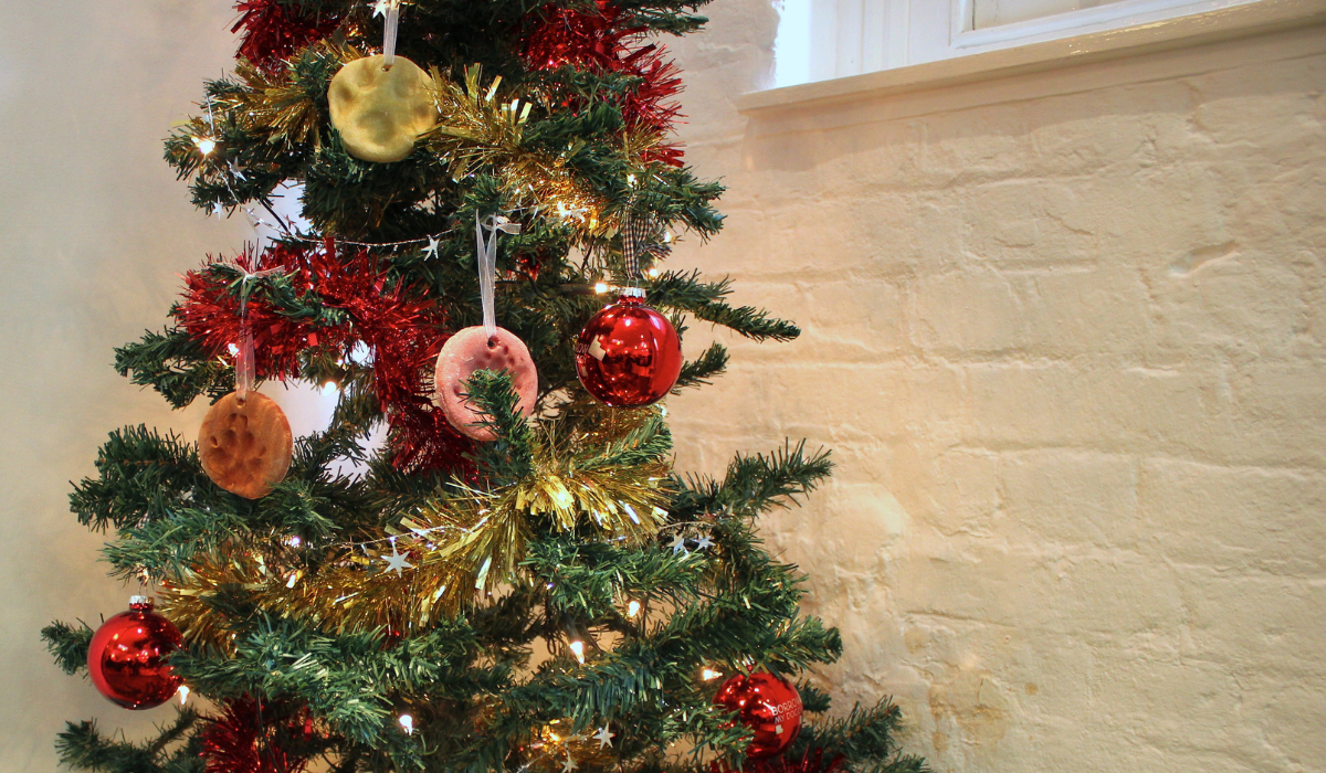 A beautifully decorated Christmas tree with DIY dog pawprint ornaments hanging from the branches.