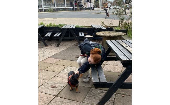 Student Amelia with her borrowed dog, Lola, the Dachshund at a dog friendly pub in the outdoors seating area