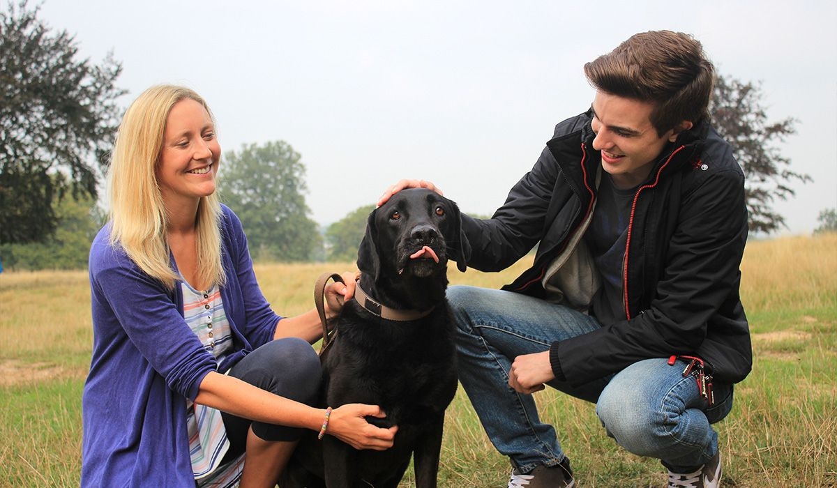 Two people and a dog are together in a park