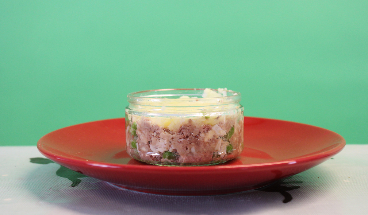 A red plate with a glass jar dish placed on top filled with Doggy Fish Cake.