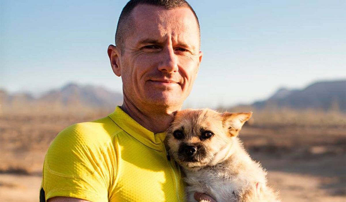 Dion and Gobi cuddle up in an open landscape with mountains in the background