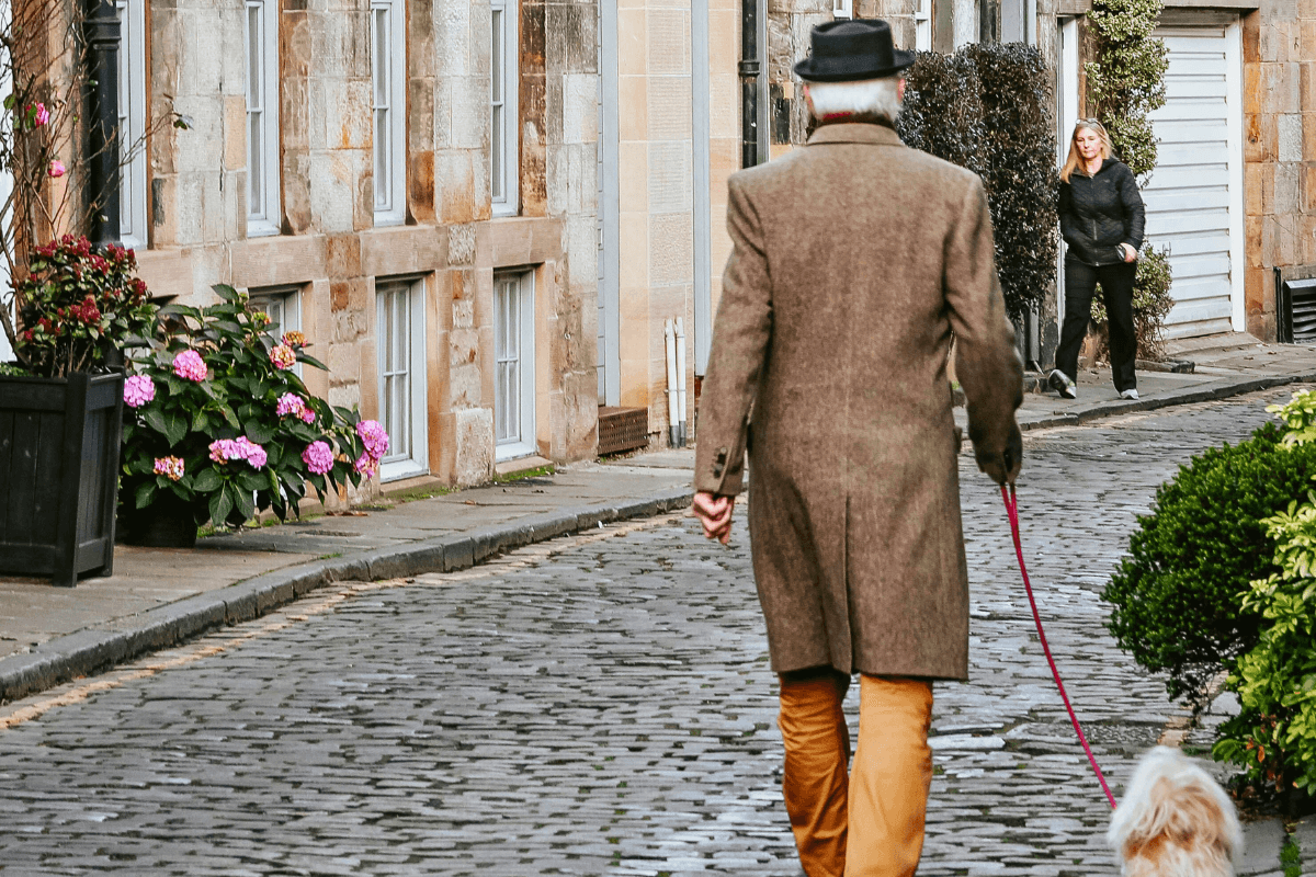 A man walks a dog along an Edinburgh Street